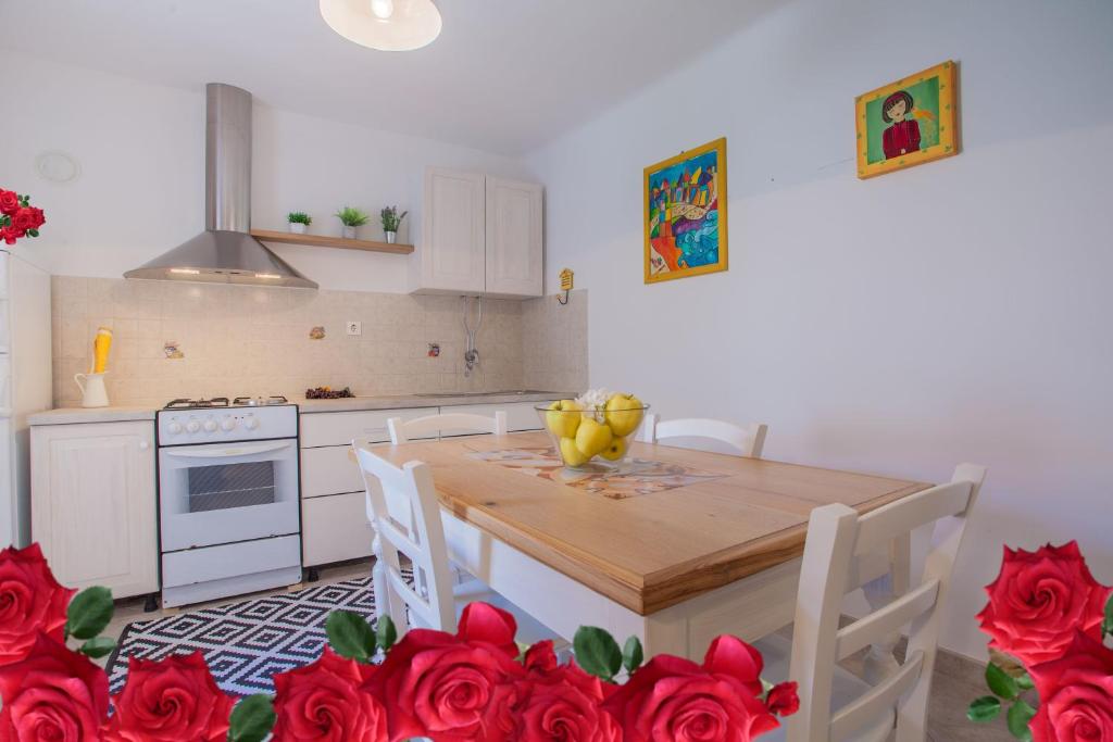 kuchnia z drewnianym stołem i czerwonymi różami w obiekcie Little prince - Your Holiday home on Cres w mieście Cres