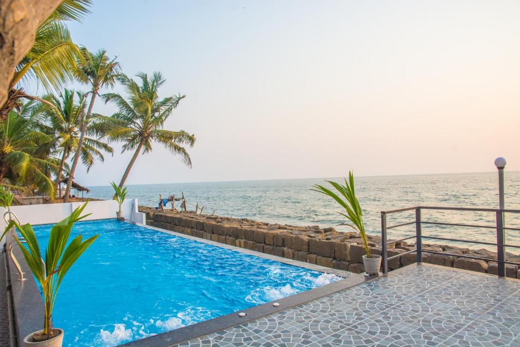a swimming pool with the ocean in the background at 36 Palms Residency - Sea View Villa in Cochin