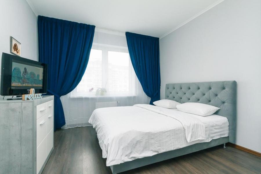Cette chambre comprend un lit avec des rideaux bleus et une télévision. dans l'établissement Уютные апартаменты на Улице Русова 7 метро 15 минут, à Kiev