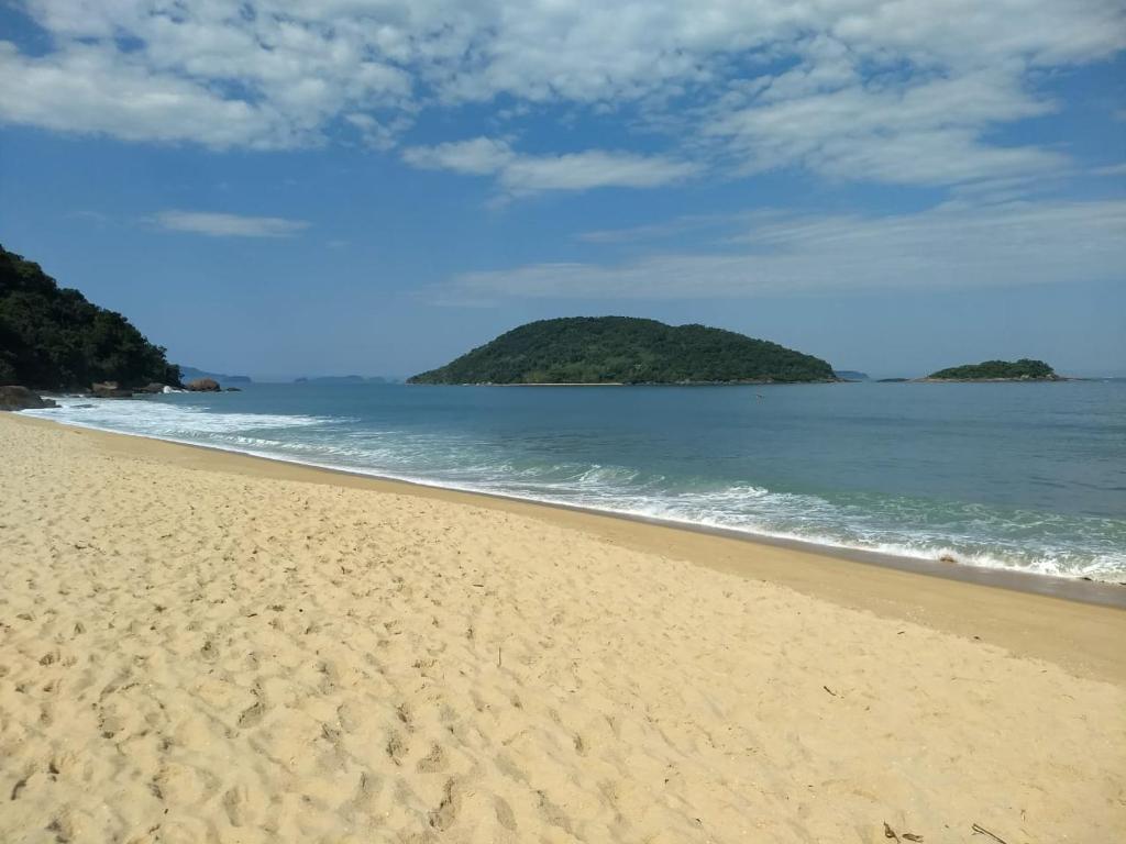 una playa de arena con una isla en el océano en Solar das Canoas Prumirim en Ubatuba