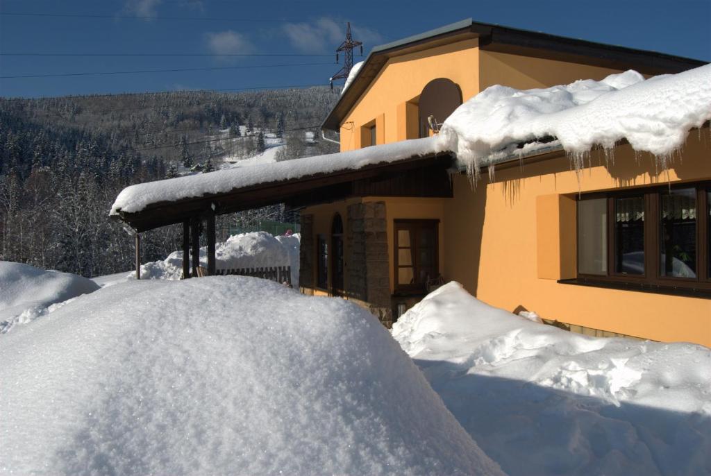 a house covered in snow next to a building at Pension Popelka in Špindlerův Mlýn