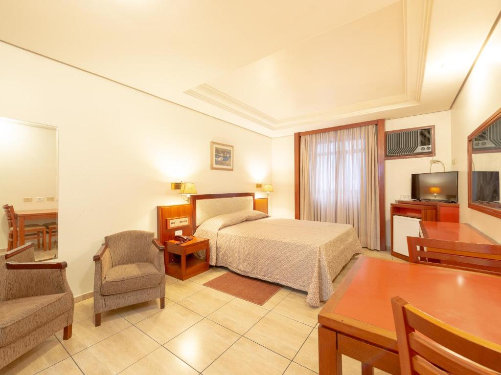 a hotel room with a bed and a table and chair at Real Castilha Hotel in Sao Paulo