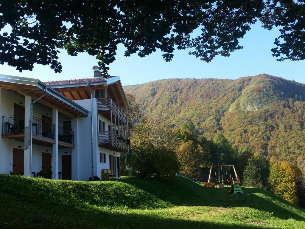 a house with a playground in front of a mountain at Garnì Fobbie in Brentonico