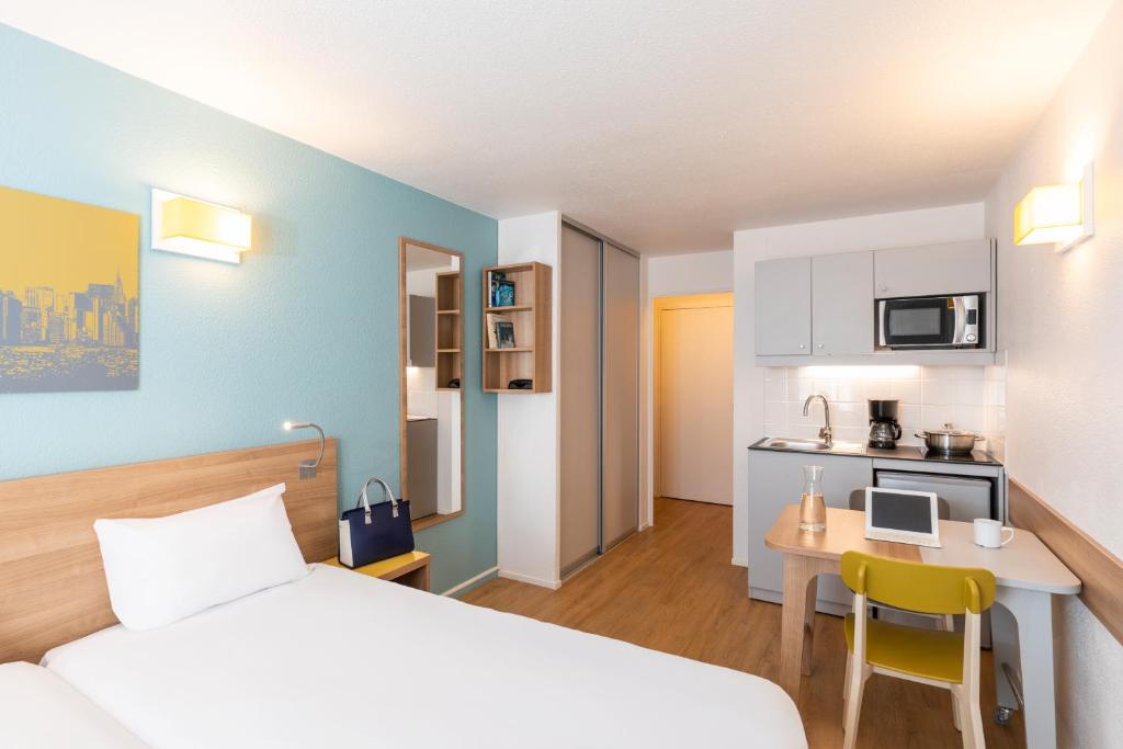 une chambre d'hôtel avec un lit, un bureau et une cuisine dans l'établissement Aparthotel Adagio Access La Défense - Place Charras, à Courbevoie