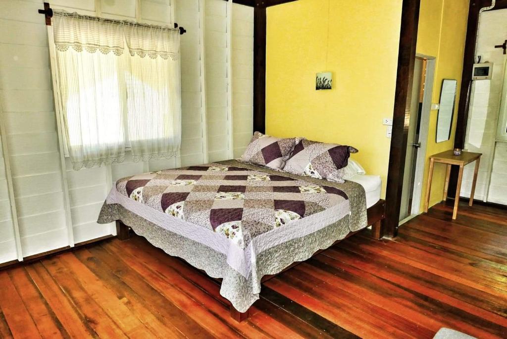 1 dormitorio con 1 cama en una habitación con suelo de madera en The Best Bungalow, en Ban Bang Chak