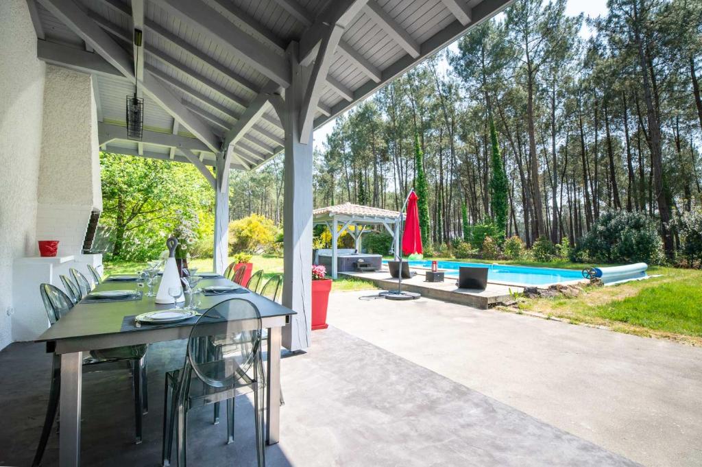 un patio con mesa, sillas y piscina en Villa Messanges (piscine & spa) en Messanges