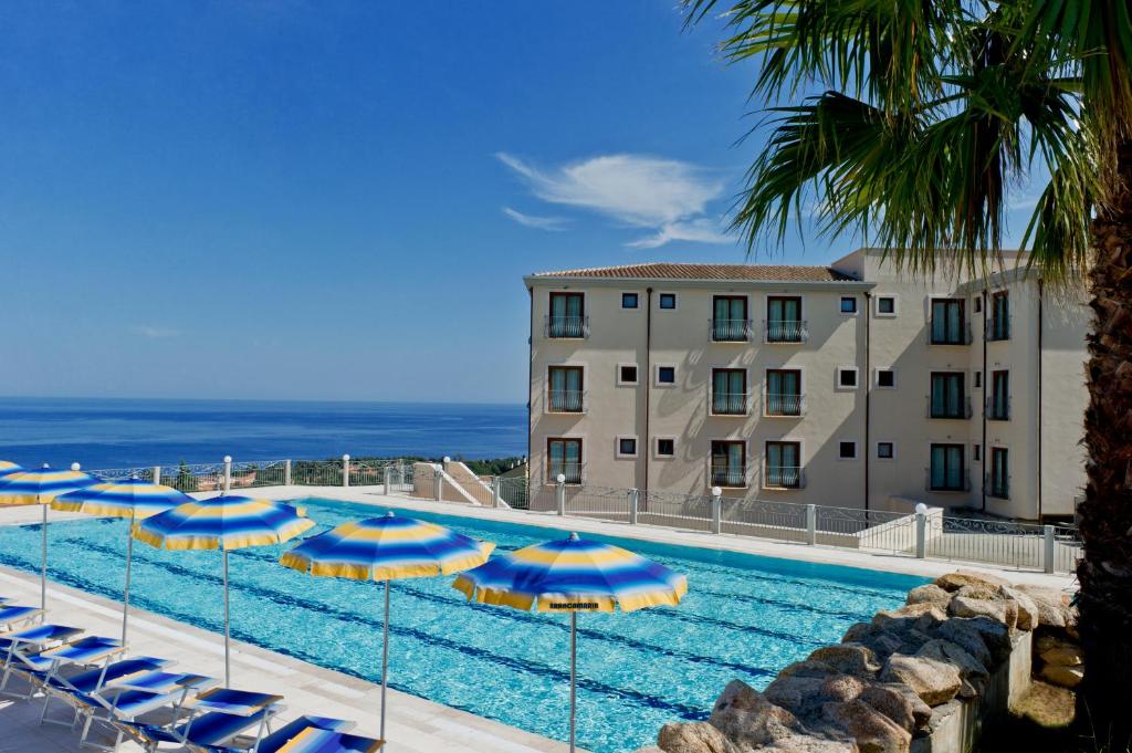 a large swimming pool with blue and yellow umbrellas at Hotel Brancamaria in Cala Gonone