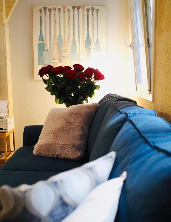 a blue couch with a vase of red roses at Esprit Bordelais in Bordeaux