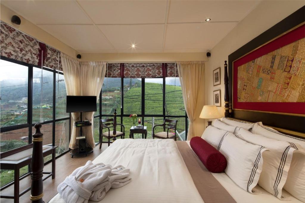 a hotel room with a large bed and a large window at CheRiz Boutique Villa Hotel in Nuwara Eliya
