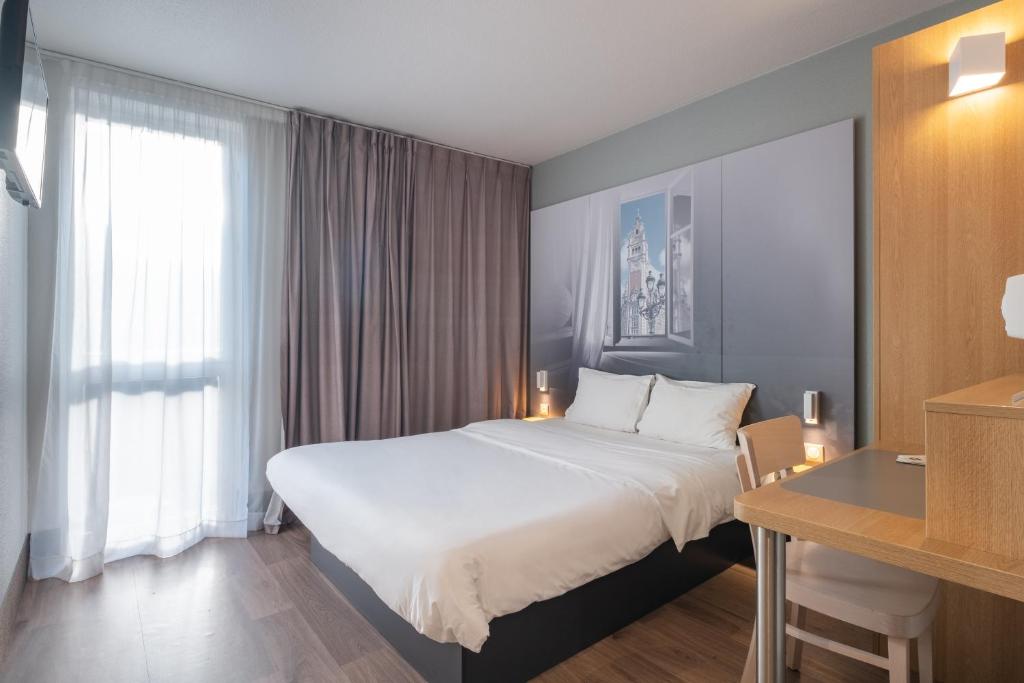 トゥールコワンにあるB&B HOTEL Lille Tourcoing Centreの大きなベッドとデスクが備わるホテルルームです。