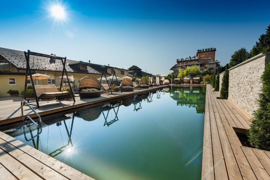 a pool of water with chairs on a wooden deck at Hotel Winzer Wellness & Kuscheln in Sankt Georgen im Attergau