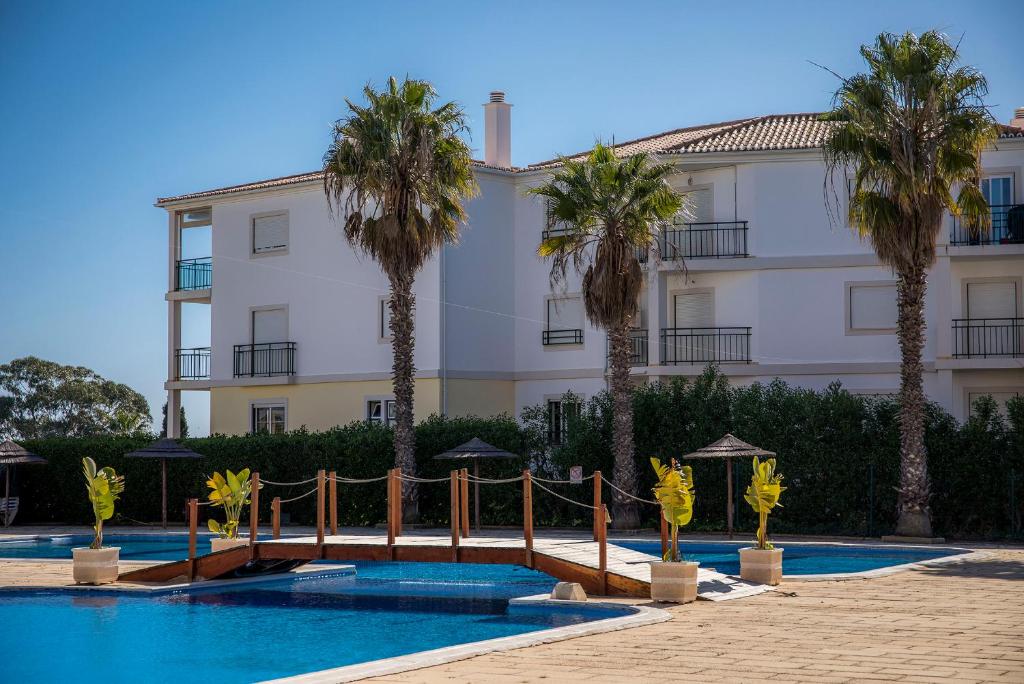 a building with palm trees in front of a swimming pool at B33 - Praia do Vau Apartment in Portimão