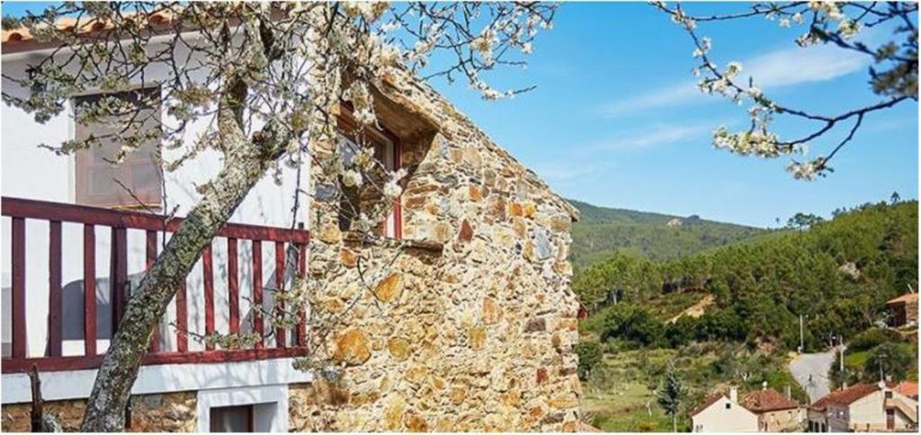 un edificio de piedra con una valla roja junto a un árbol en Casas da Encosta, en Proença-a-Nova