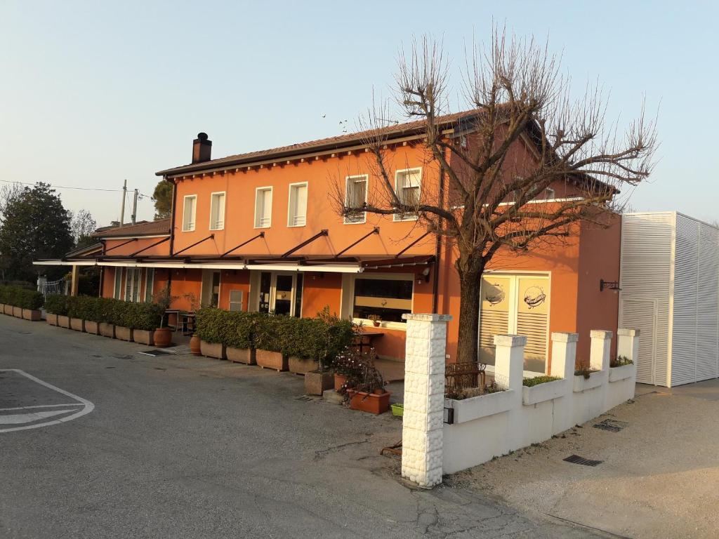 un edificio arancione con un albero di fronte di Locanda Mirafiori a San Donà di Piave