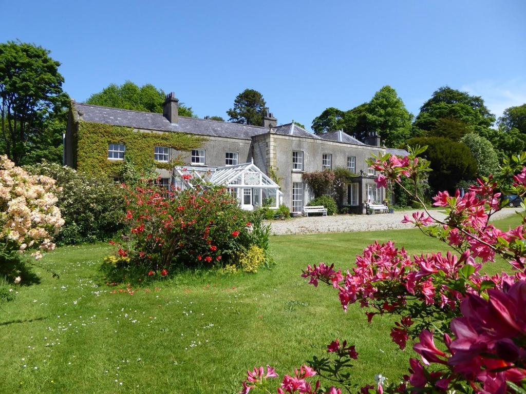una gran casa de piedra con flores en el patio en O'Harabrook Country House, en Ballymoney