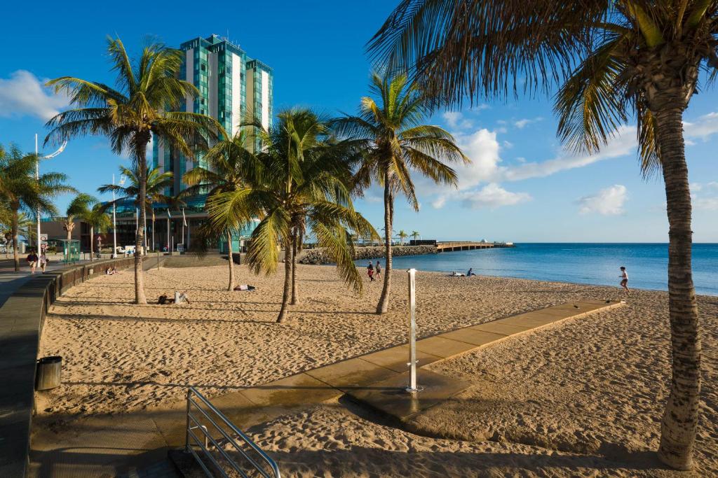 a beach with palm trees and a building at Lanzalina in Arrecife