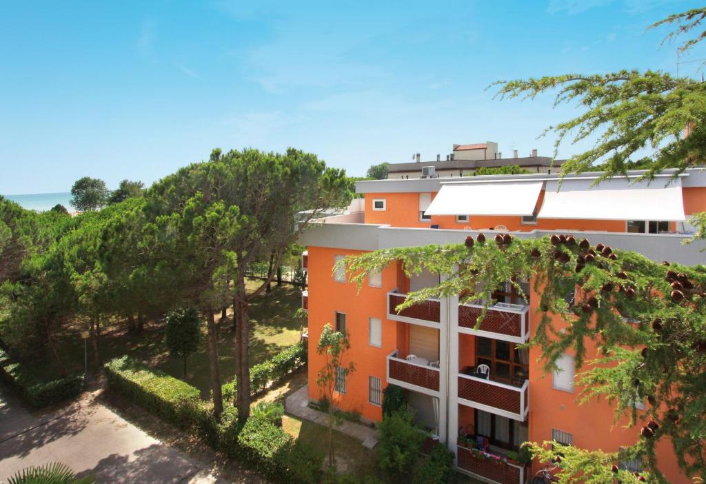 un edificio arancione con alberi e l'oceano sullo sfondo di Appartamenti Angela e Pordenone a Bibione