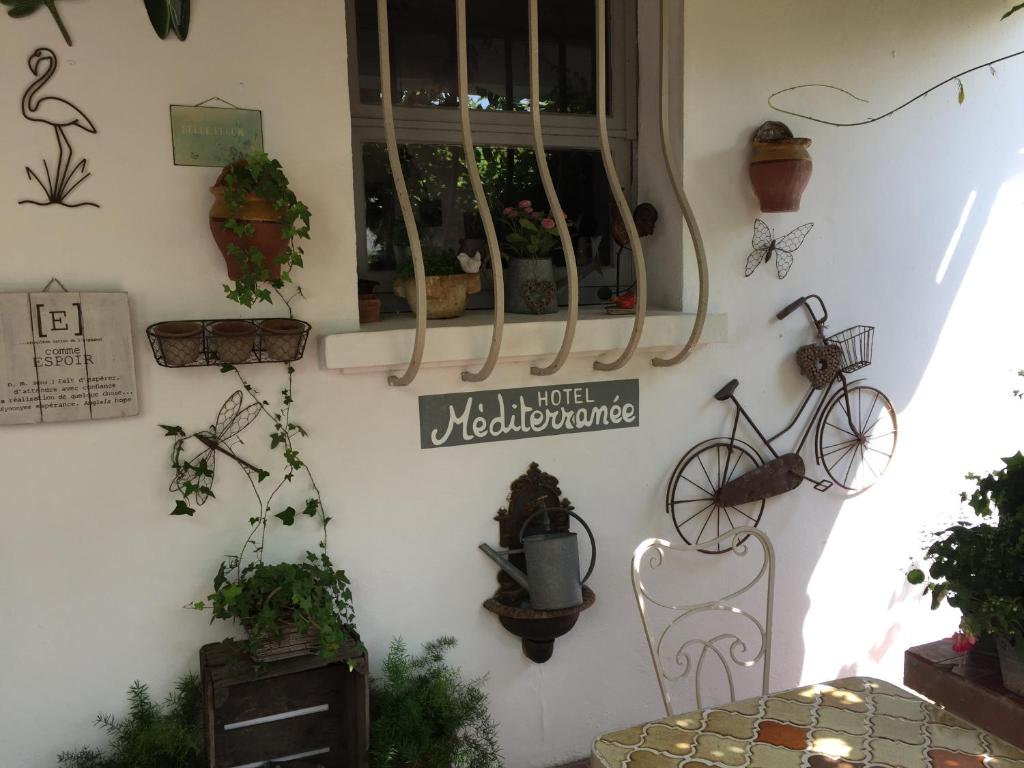 a wall with potted plants and a sign on it at Hotel Le Méditérranée in Saintes-Maries-de-la-Mer