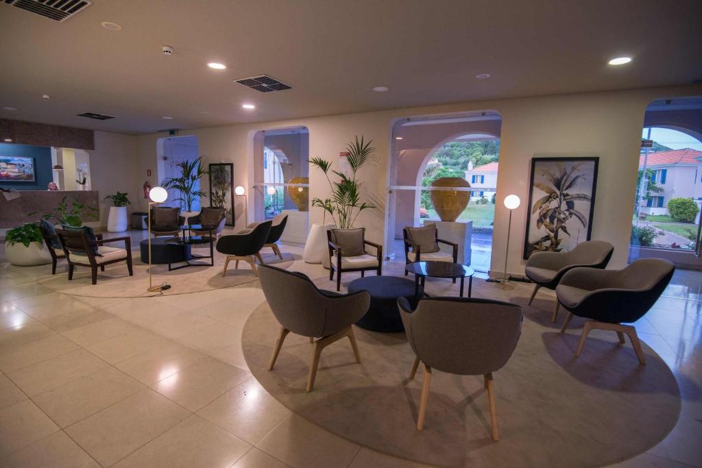 a waiting room with chairs and tables and windows at Azoris Faial Garden – Resort Hotel in Horta