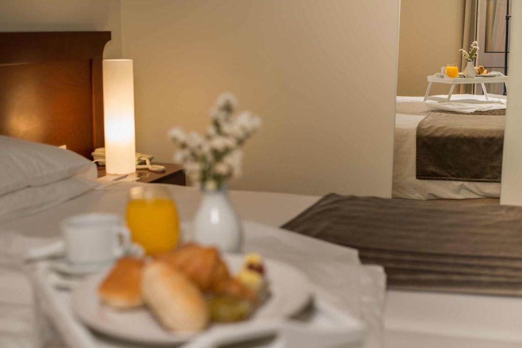 a plate of food on a table next to a bed at Azoris Faial Garden – Resort Hotel in Horta