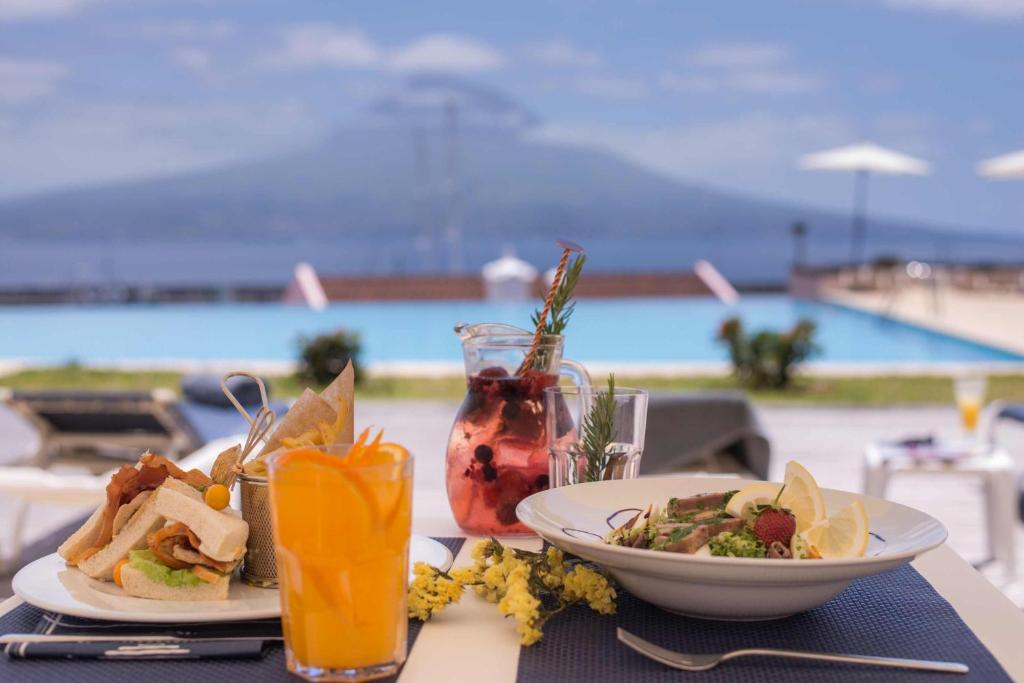 a table with two plates of food and a drink at Azoris Faial Garden – Resort Hotel in Horta