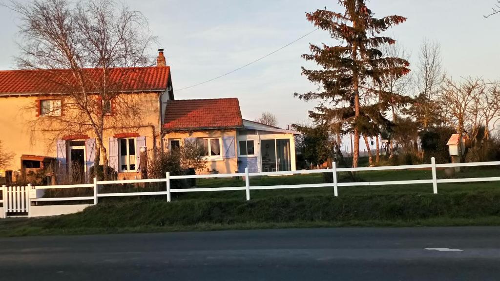 une maison avec une clôture blanche devant elle dans l'établissement Gîte Sèvremoine Bois Buteau, à Montfaucon