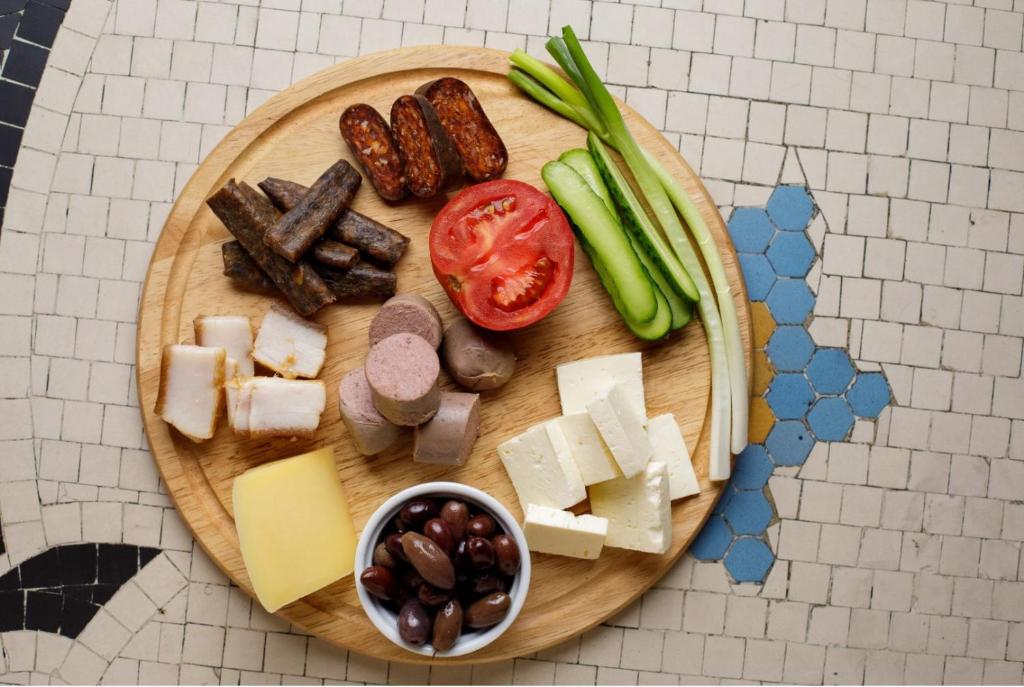 a plate of food with meats and cheese and vegetables at Pensiunea Junior in Cluj-Napoca