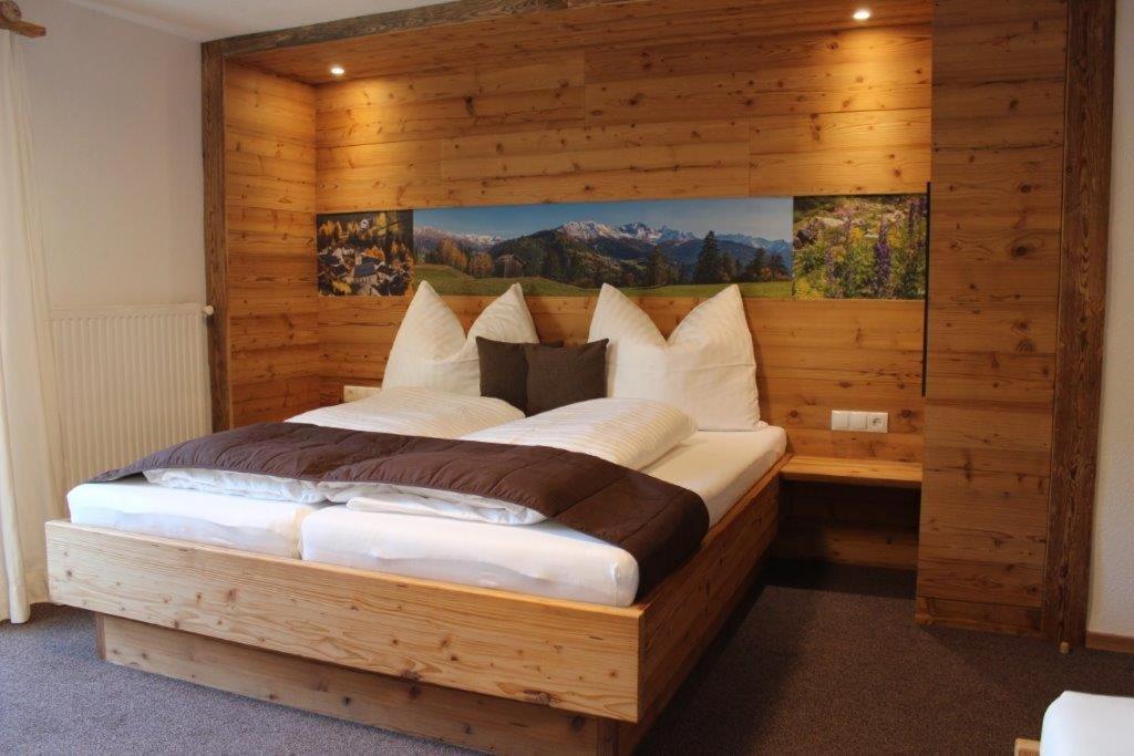 a bedroom with a large bed with a wooden wall at Haus Martina Buchhammer in Fendels