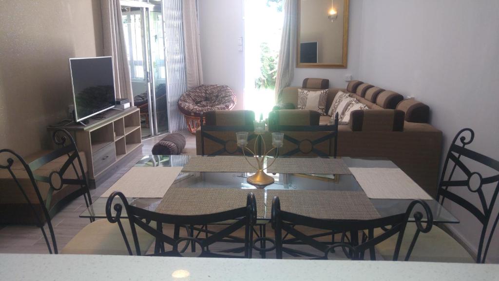 een woonkamer met een tafel en stoelen en een bank bij Beach Apartment in Pereybere