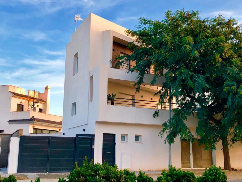 un edificio blanco con un árbol delante en Vivienda Avenida de la Manzanilla, en Sanlúcar de Barrameda