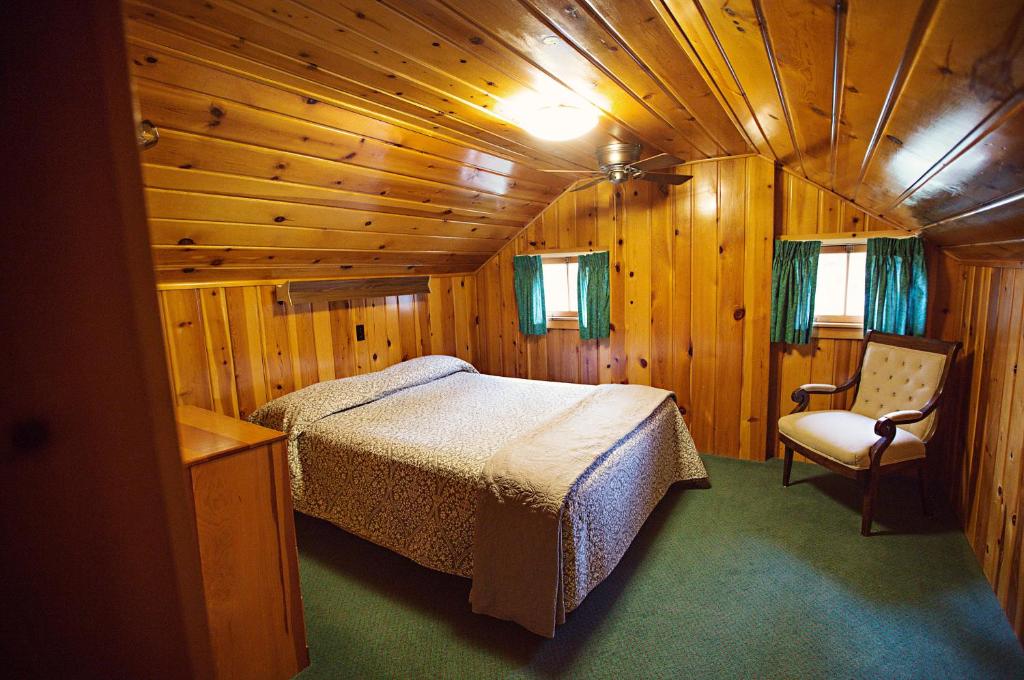 a bedroom in a wooden cabin with a bed and a chair at Idlewilde by the River in Estes Park