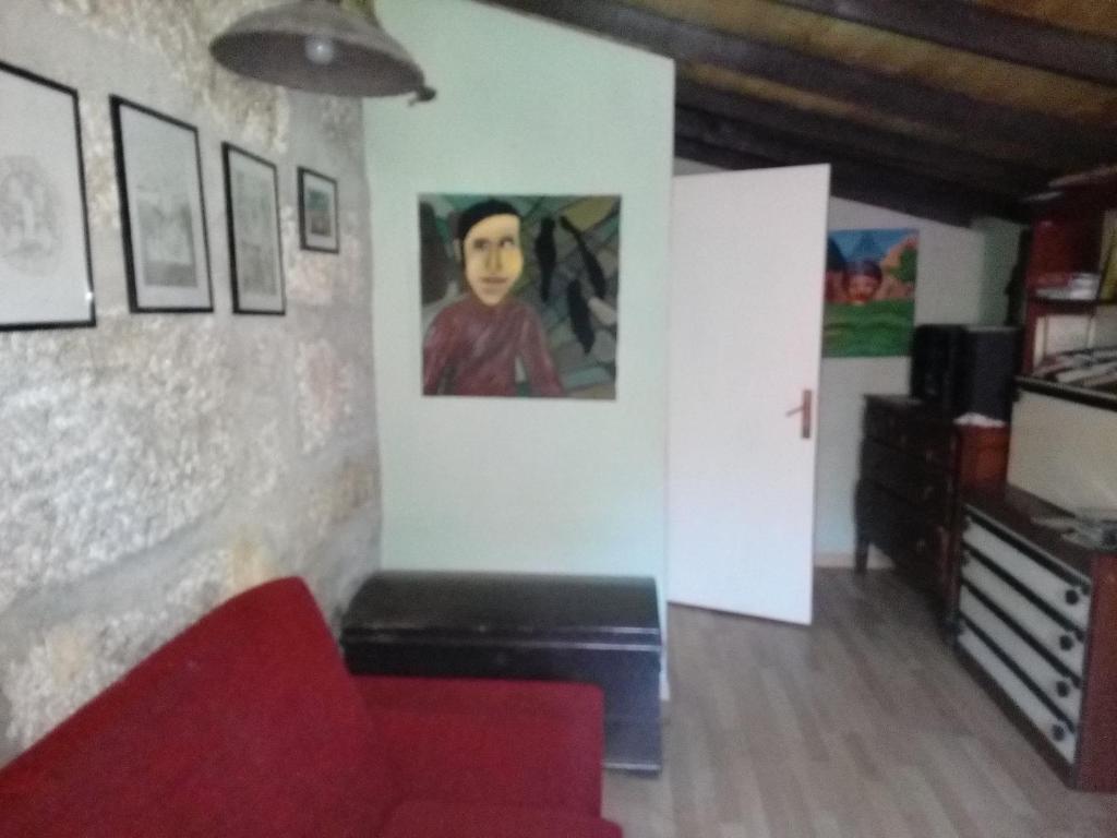 a living room with a red couch and paintings on the wall at Casa de campo in Lovelhe