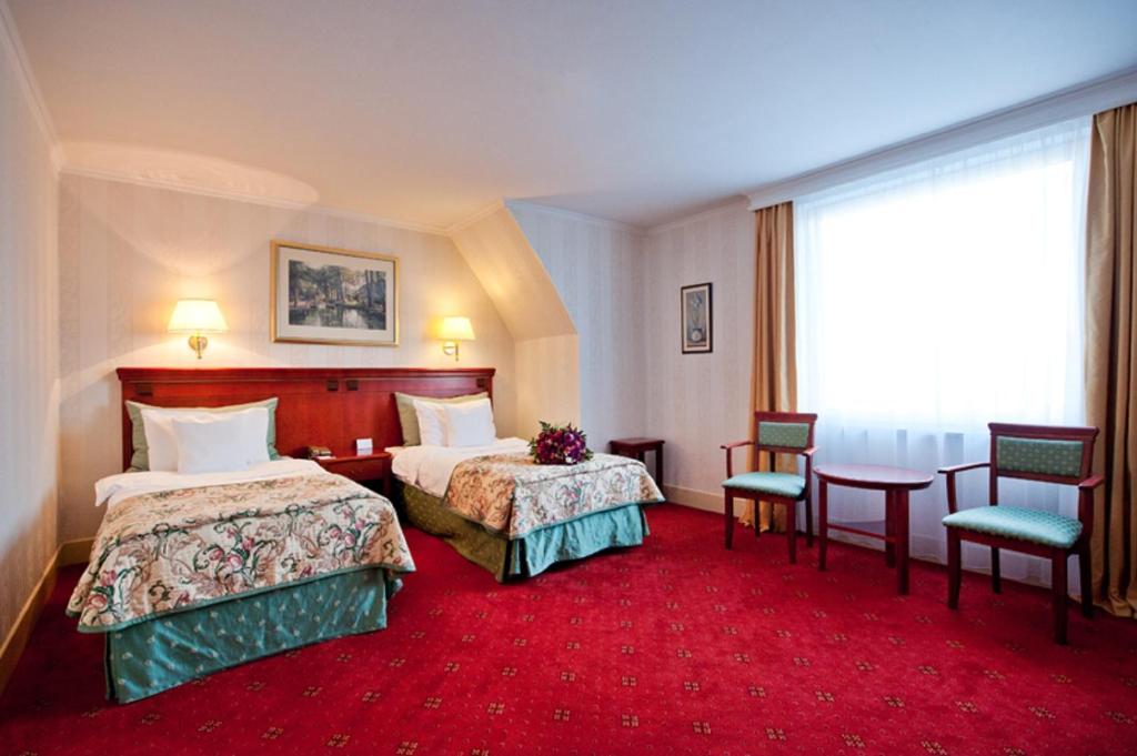 a hotel room with two beds and a table and chairs at Hotel Mazurkas in Ożarów Mazowiecki
