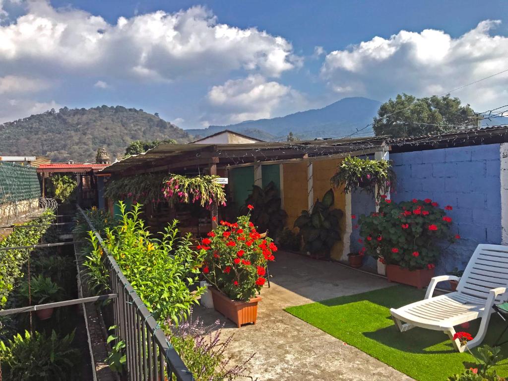 ein Haus mit einer Terrasse mit Blumen und einem Stuhl in der Unterkunft Hostal Antigua in Antigua Guatemala