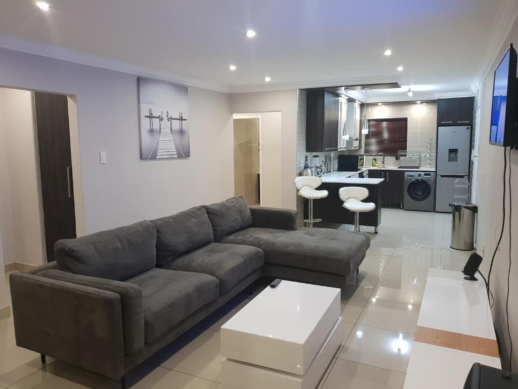 ein Wohnzimmer mit einem Sofa und einer Küche in der Unterkunft Semeni Asante 16 in Johannesburg