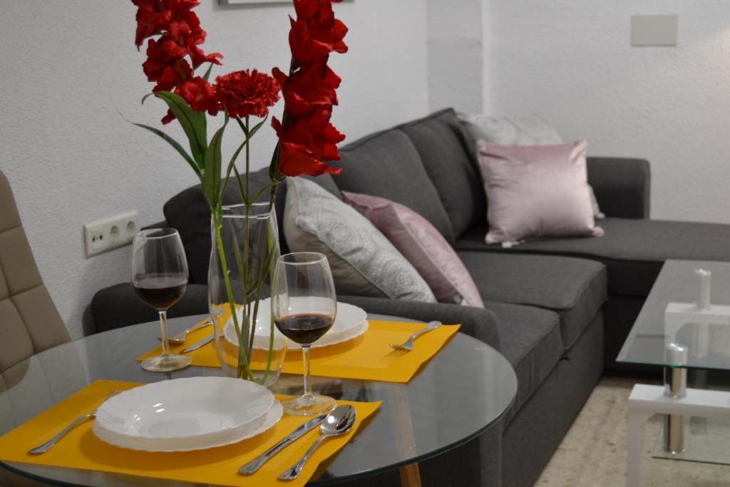 een tafel met twee glazen wijn en rode bloemen erop bij Nuevo Sueño del Alcazar in Córdoba