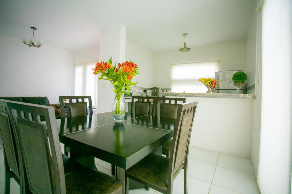 a dining room table with a vase of flowers on it at Casa moderna en segura Residencial Hacienda Chetumal in Chetumal