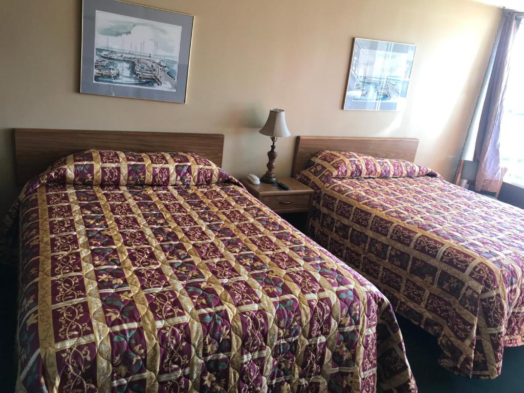a hotel room with two beds and a lamp at Budget Host Village Inn in Kirksville