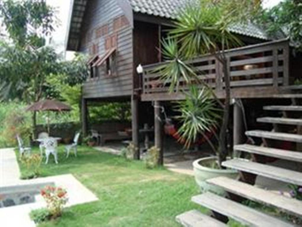 a house with a staircase leading to a yard at Ayothaya Riverside House in Phra Nakhon Si Ayutthaya