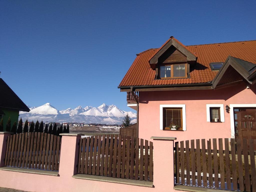 różowy dom z ogrodzeniem i górami w tle w obiekcie Villa Maria w Wielkiej Łomnicy