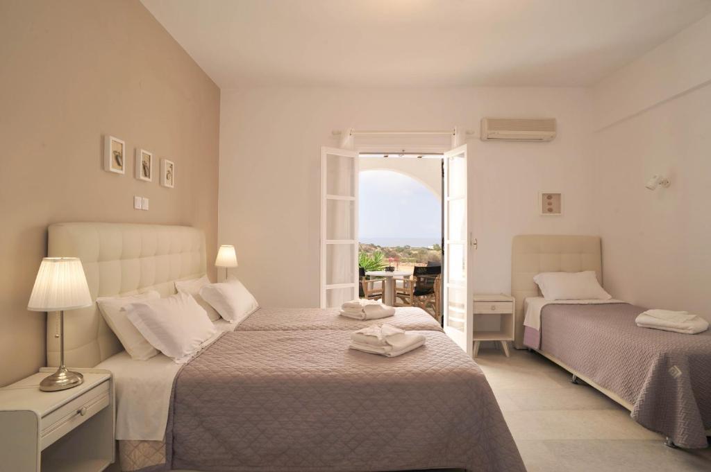 a white bedroom with two beds and a window at Scala Apartments in Kastraki Naxou