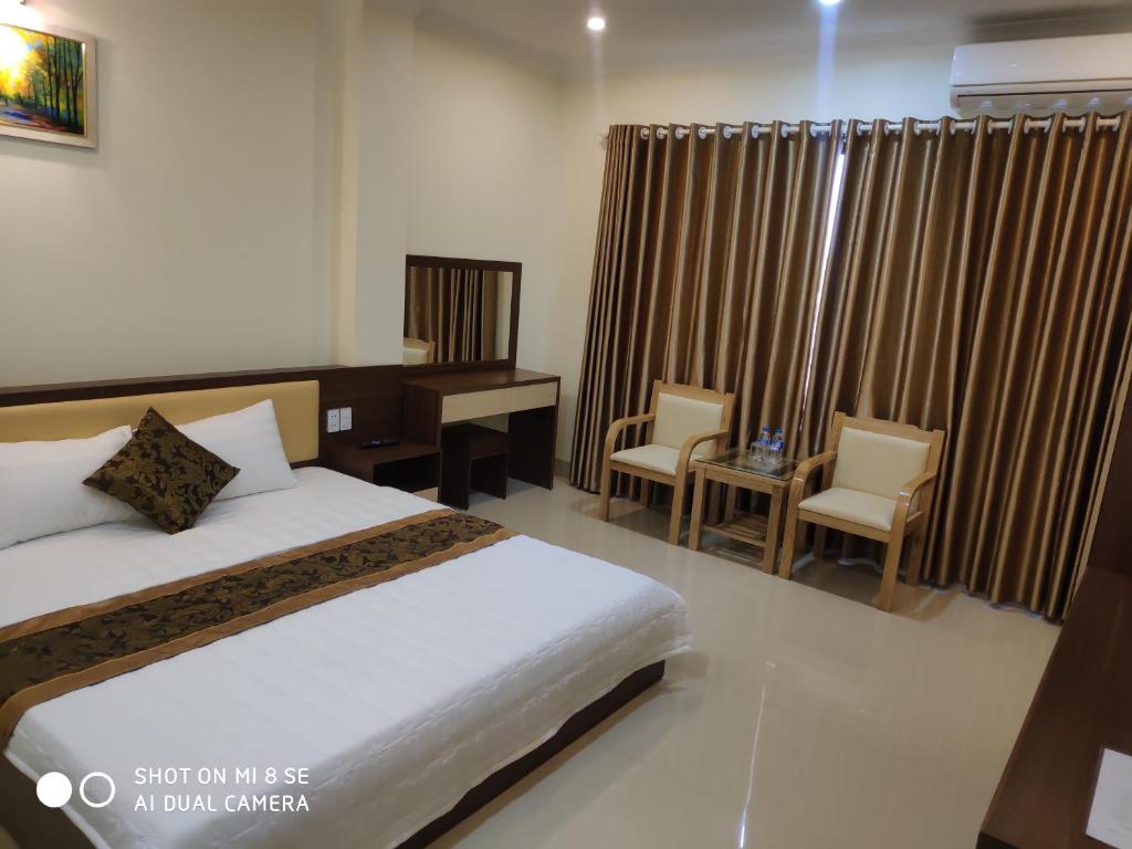 1 dormitorio con 1 cama, escritorio y sillas en Ngọc Anh Hotel, en Ha Long