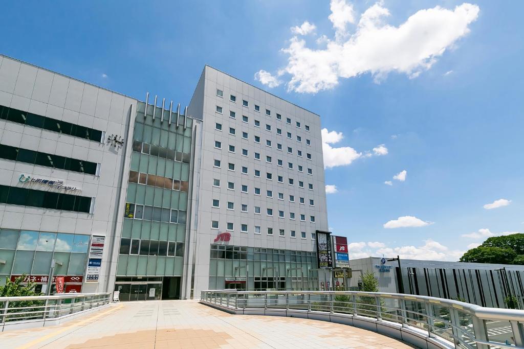 a large white building with a bridge in front of it at Sotetsu Fresa Inn Nagano-Ueda in Ueda