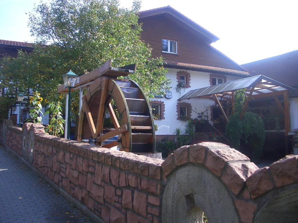eine Steinmauer mit einem Wasserrad vor einem Haus in der Unterkunft Zur Mühle in Mörlenbach