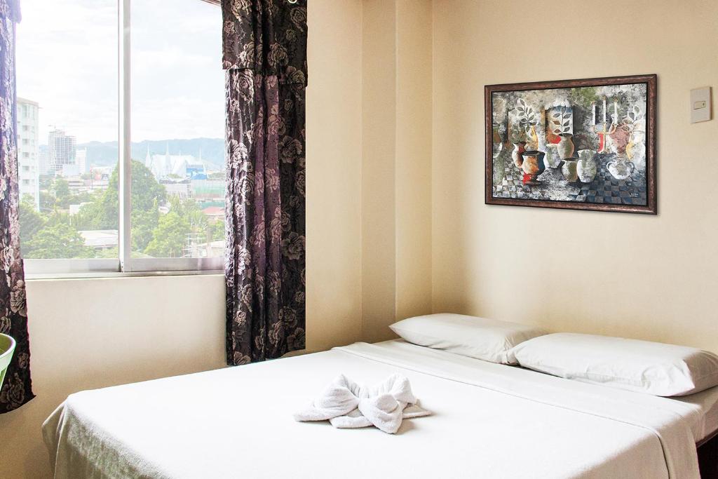 2 letti in una camera con finestra e quadro di Allson's Inn a Cebu City