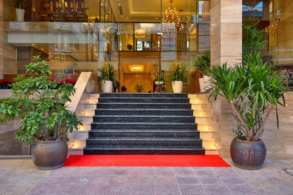 a staircase in a building with a red carpet and potted plants at Sata Hotel in Nha Trang