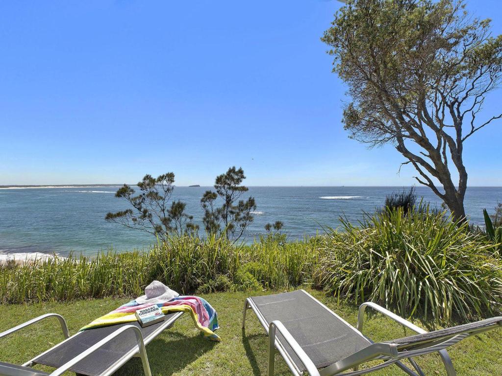a table and chairs sitting next to the ocean at Stunning Ocean Views in Norah Head