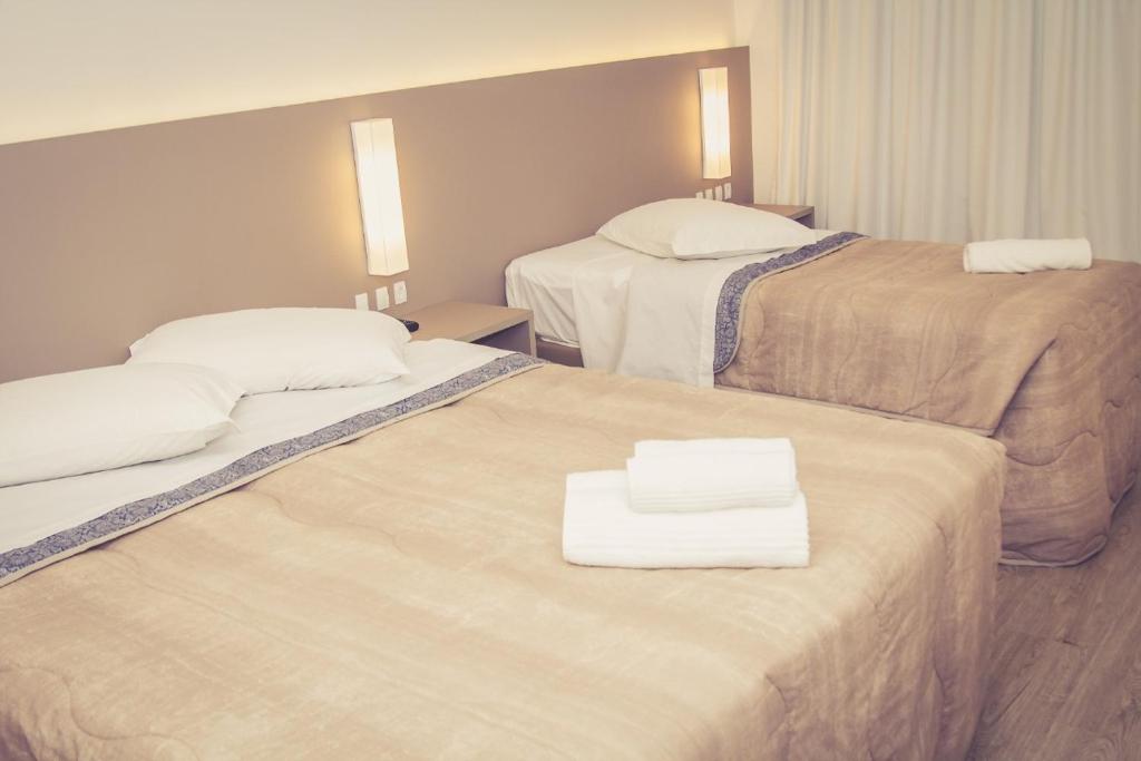 um quarto de hotel com duas camas com toalhas em HOTEL LUAR ATLANTICO no Balneário Camboriú