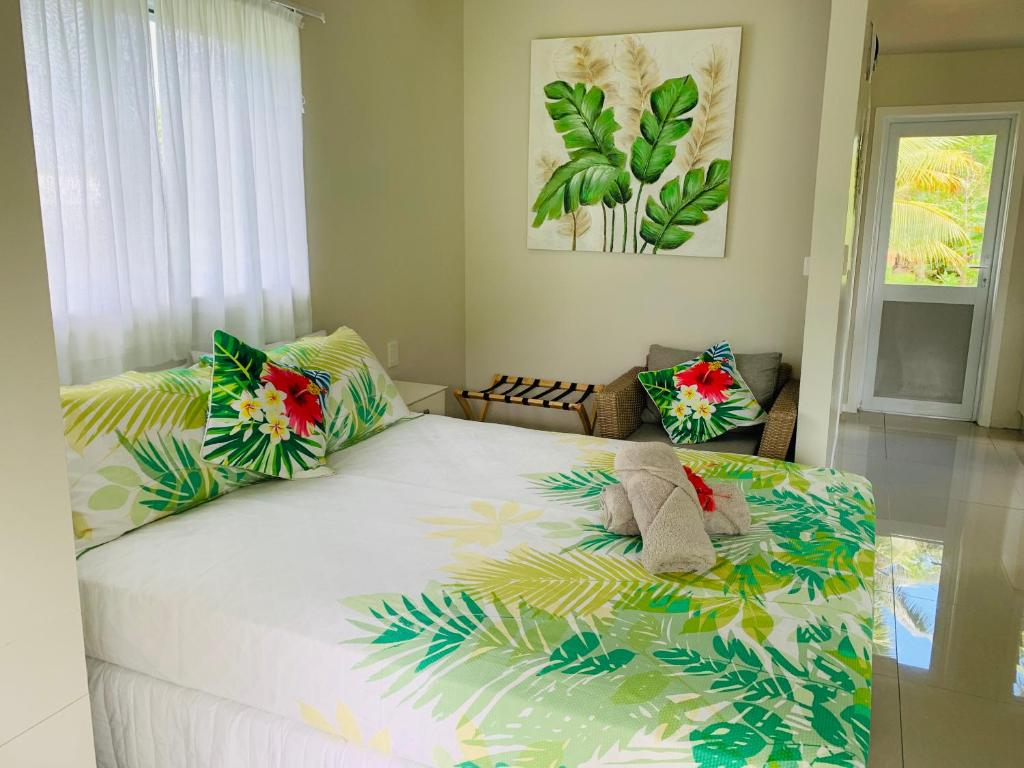 um quarto com uma grande cama branca com almofadas tropicais em Muri Villas em Rarotonga