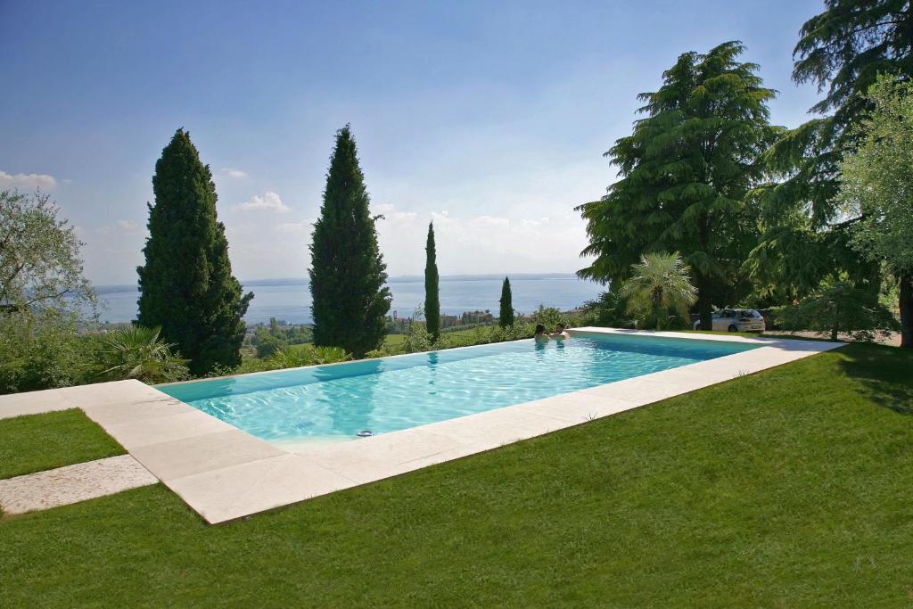 une piscine au milieu d'une pelouse avec des arbres dans l'établissement Relais Colle San Giorgio, à Bardolino
